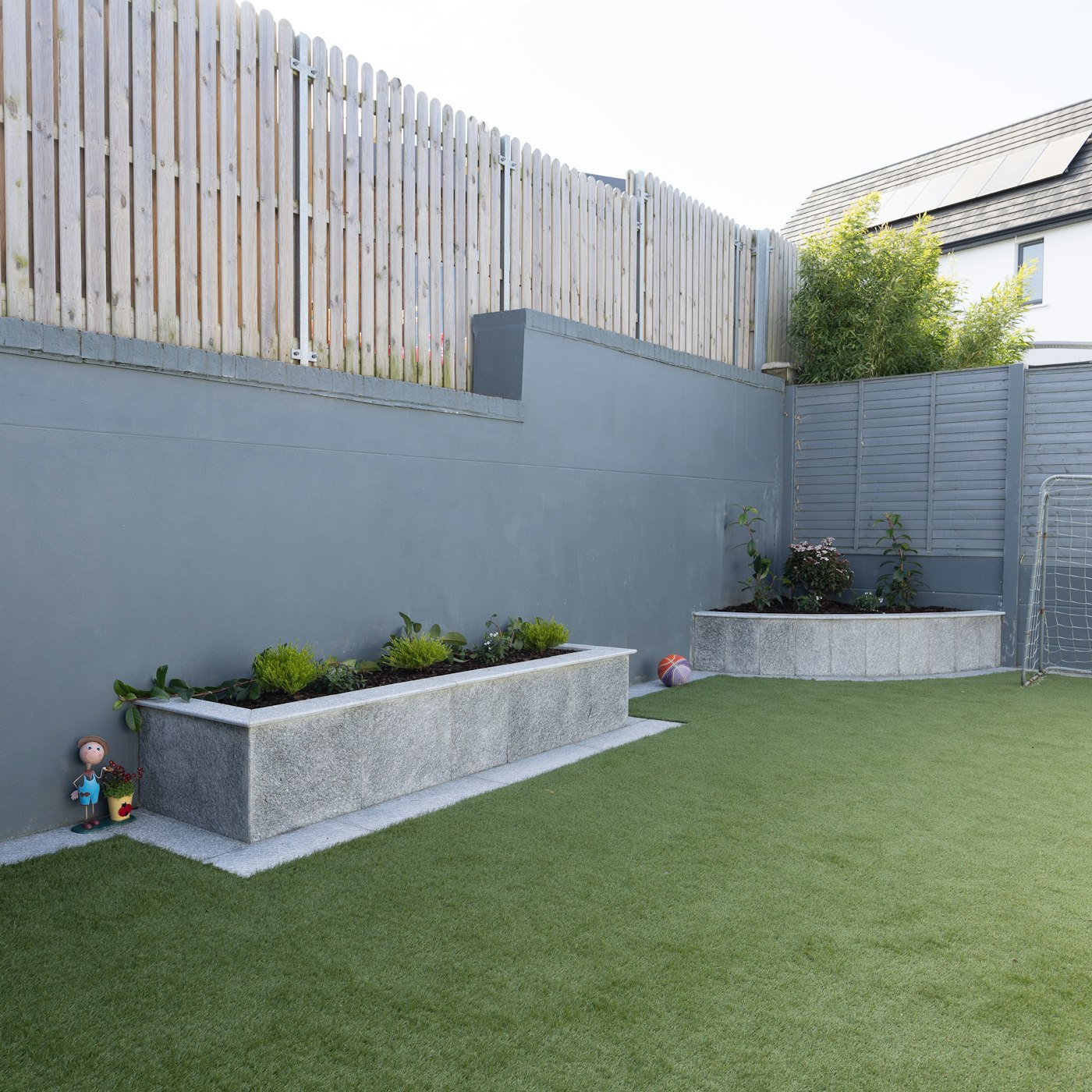 Backyard with artificial grass and a concrete planter